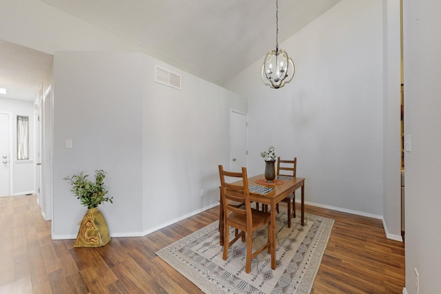 dining space featuring a notable chandelier, baseboards, vaulted ceiling, visible vents, and wood finished floors