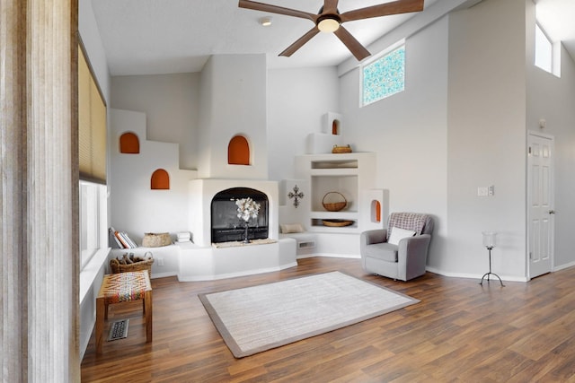 living area featuring visible vents, ceiling fan, high vaulted ceiling, and wood finished floors