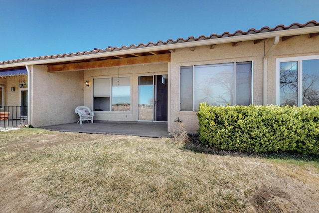 back of property with a patio area, stucco siding, and a lawn