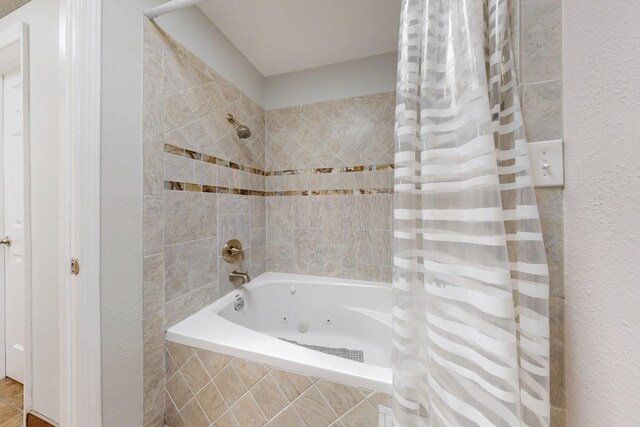 bathroom featuring tiled shower / bath combo and a textured wall