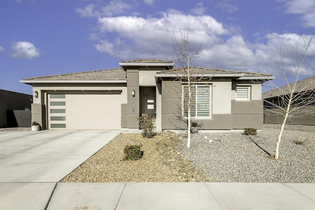 prairie-style home featuring concrete driveway, stucco siding, and an attached garage