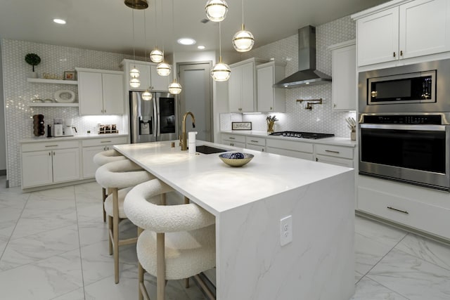 kitchen with a sink, appliances with stainless steel finishes, marble finish floor, and wall chimney exhaust hood