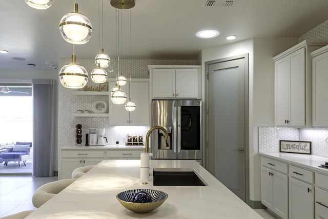 kitchen with stainless steel fridge with ice dispenser, hanging light fixtures, tasteful backsplash, and white cabinets