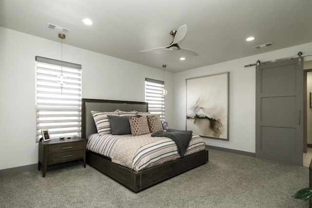 bedroom with a barn door, visible vents, light colored carpet, and baseboards