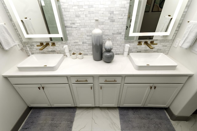 bathroom with tasteful backsplash, marble finish floor, and a sink