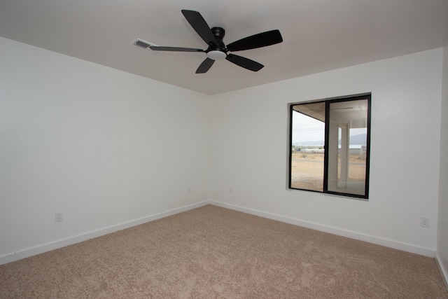 carpeted spare room with visible vents, a ceiling fan, and baseboards
