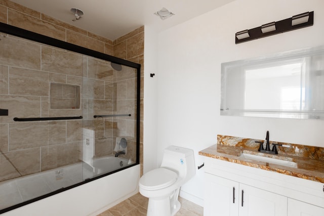 bathroom featuring tile patterned floors, vanity, enclosed tub / shower combo, and toilet