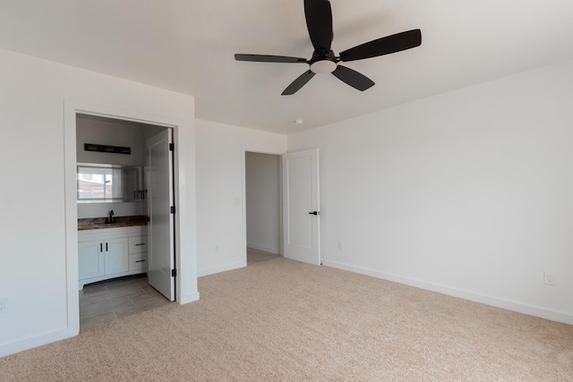 unfurnished bedroom featuring light carpet, connected bathroom, a sink, baseboards, and ceiling fan