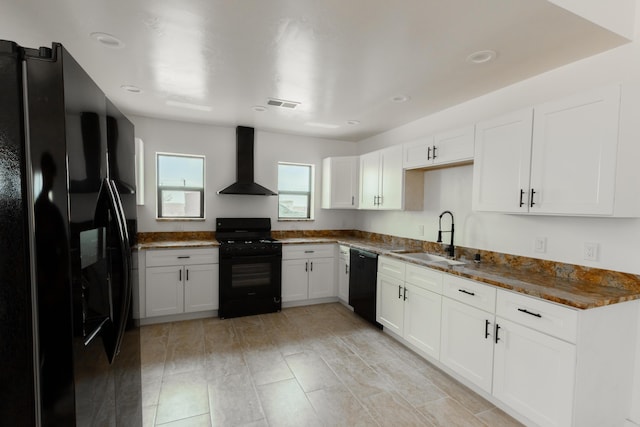 kitchen featuring wall chimney exhaust hood, a sink, visible vents, white cabinetry, and black appliances