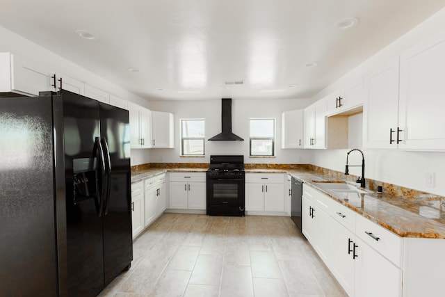 kitchen with white cabinets, wall chimney range hood, a sink, and black appliances