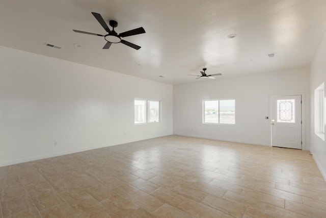 unfurnished room featuring a ceiling fan, visible vents, and plenty of natural light