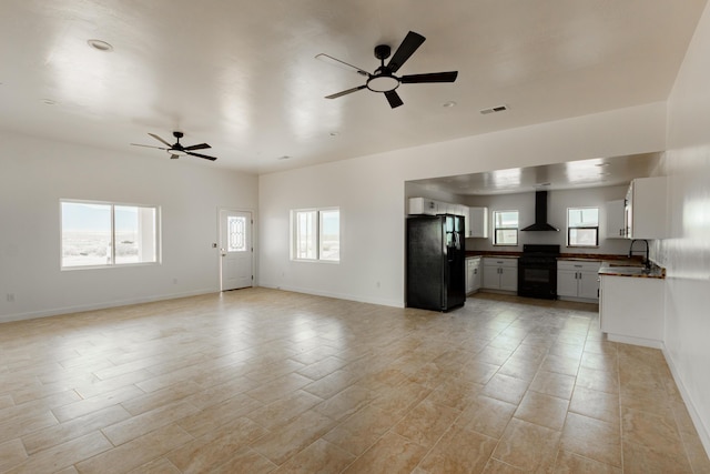 unfurnished living room with visible vents, a ceiling fan, and a wealth of natural light