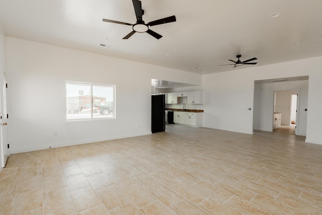 unfurnished living room with baseboards, visible vents, a sink, and ceiling fan