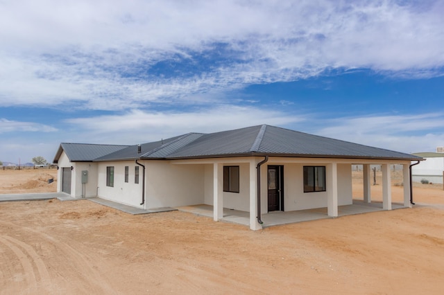 back of house featuring stucco siding, a patio, and metal roof