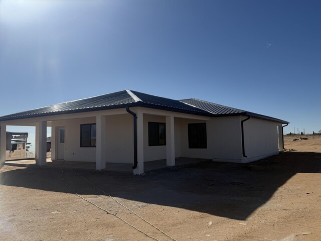 rear view of house with stucco siding and metal roof