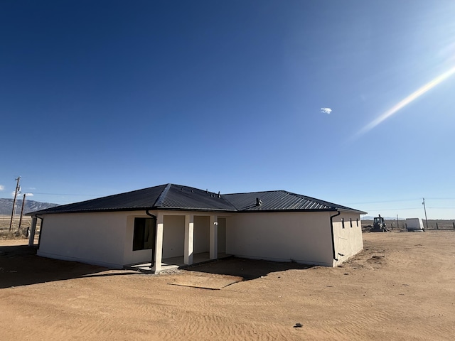 rear view of house with metal roof and stucco siding