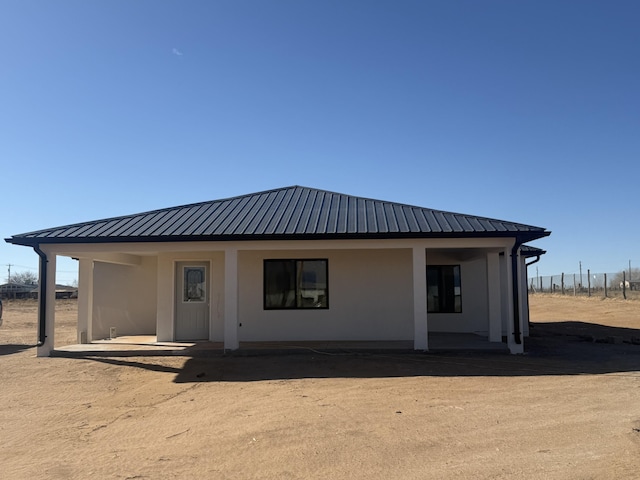 view of front facade with fence, metal roof, and stucco siding