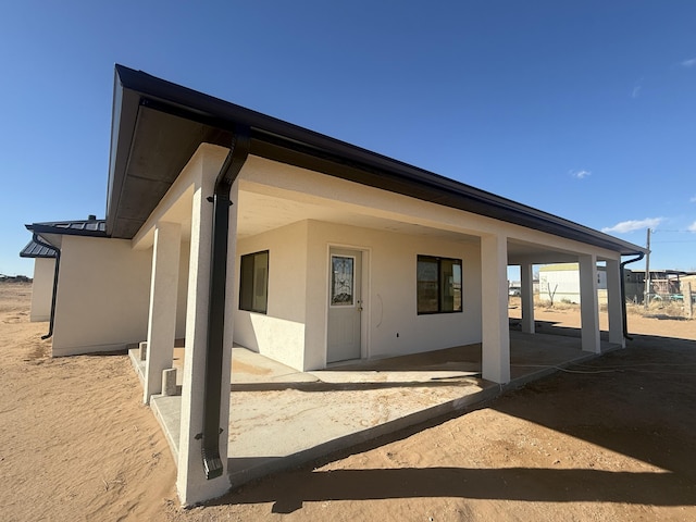rear view of house with a patio area and stucco siding