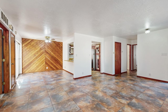 12522 Singing Arrow Ave SE, Albuquerque, NM 87123 - spare room featuring a textured ceiling, wood walls, baseboards, and a ceiling fan