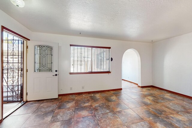 12522 Singing Arrow Ave SE, Albuquerque, NM 87123 - foyer entrance featuring visible vents, baseboards, arched walkways, and a textured ceiling
