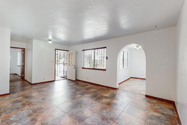 12522 Singing Arrow Ave SE, Albuquerque, NM 87123 - spare room featuring visible vents, baseboards, arched walkways, and a textured ceiling