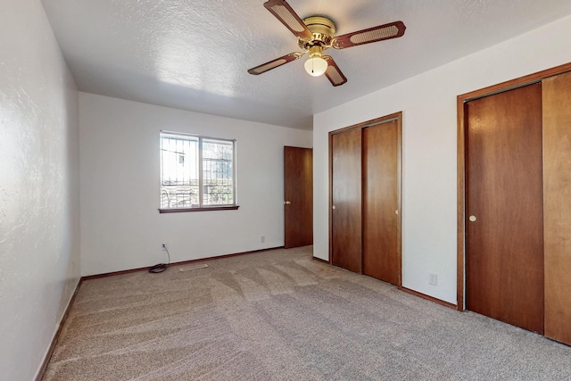 12522 Singing Arrow Ave SE, Albuquerque, NM 87123 - unfurnished bedroom featuring baseboards, two closets, a ceiling fan, carpet, and a textured ceiling