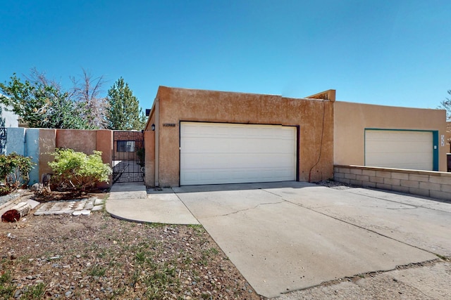 12522 Singing Arrow Ave SE, Albuquerque, NM 87123 - view of front of property featuring an attached garage, concrete driveway, stucco siding, and a gate