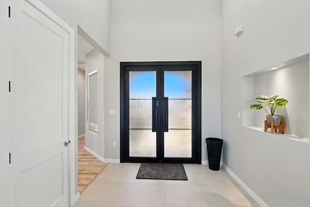 entrance foyer with baseboards and a towering ceiling