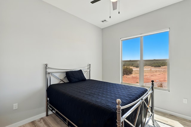 bedroom featuring baseboards, ceiling fan, light wood-type flooring, and visible vents