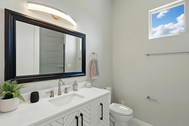 bathroom featuring toilet, baseboards, and vanity