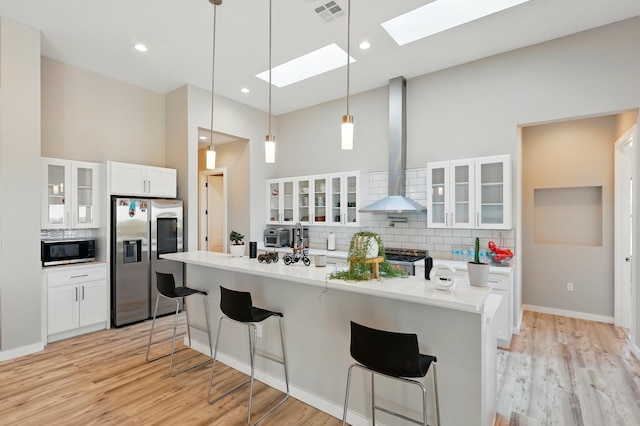 kitchen featuring visible vents, wall chimney exhaust hood, tasteful backsplash, a skylight, and stainless steel appliances
