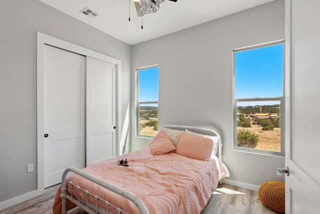 bedroom featuring a ceiling fan, baseboards, wood finished floors, visible vents, and a closet