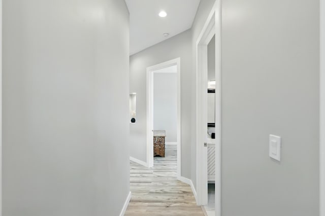 hall featuring recessed lighting, baseboards, and light wood-type flooring