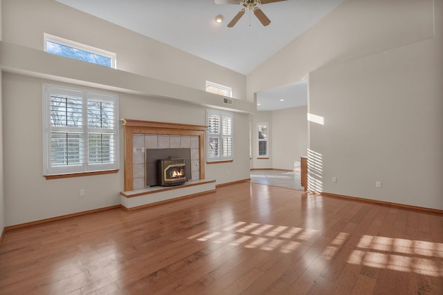 unfurnished living room with hardwood / wood-style floors, high vaulted ceiling, a ceiling fan, and baseboards