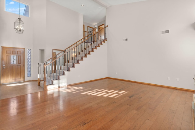 entrance foyer with a towering ceiling, stairs, visible vents, and baseboards