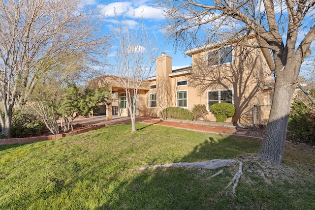 back of property featuring a yard, stucco siding, and a chimney