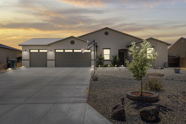 single story home with concrete driveway, metal roof, stucco siding, and a garage