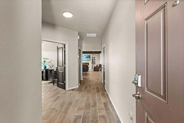 hall with light wood-style floors, baseboards, and visible vents