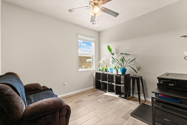 sitting room featuring light wood-style floors, ceiling fan, a textured ceiling, visible vents, and baseboards
