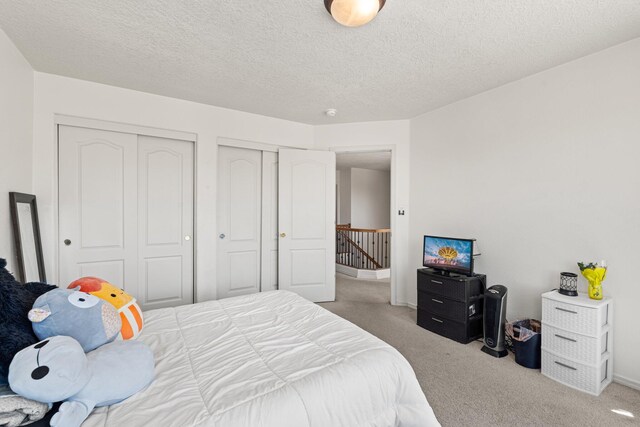 10532 Box Canyon Pl NW, Albuquerque, NM 87114 - bedroom featuring light carpet, two closets, baseboards, and a textured ceiling