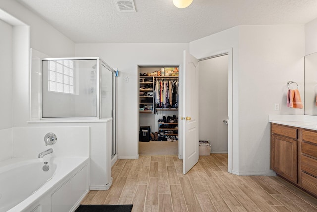 10532 Box Canyon Pl NW, Albuquerque, NM 87114 - full bathroom featuring wood finished floors, a stall shower, vanity, a bath, and a textured ceiling