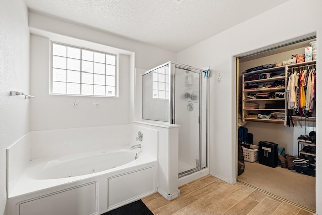 10532 Box Canyon Pl NW, Albuquerque, NM 87114 - bathroom with wood finished floors, a shower stall, a whirlpool tub, a walk in closet, and a textured ceiling