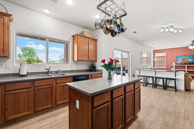 10532 Box Canyon Pl NW, Albuquerque, NM 87114 - kitchen featuring a sink, a textured ceiling, light wood-style floors, plenty of natural light, and brown cabinetry