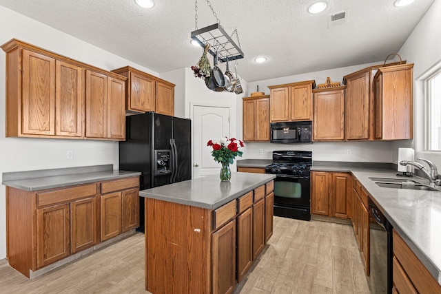 10532 Box Canyon Pl NW, Albuquerque, NM 87114 - kitchen featuring a sink, black appliances, brown cabinetry, light wood-type flooring, and a textured ceiling