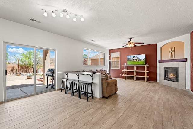 10532 Box Canyon Pl NW, Albuquerque, NM 87114 - living area featuring wood finished floors, a textured ceiling, a tile fireplace, and a ceiling fan