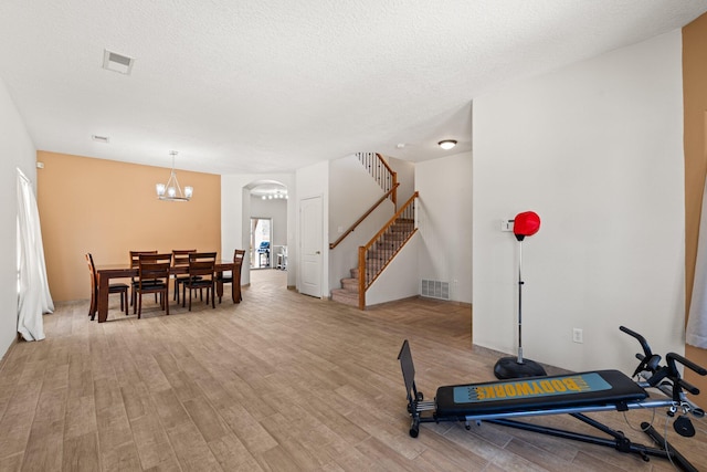 10532 Box Canyon Pl NW, Albuquerque, NM 87114 - exercise area with light wood-type flooring, arched walkways, a chandelier, and a textured ceiling