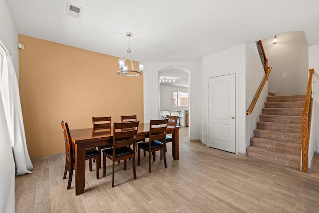 10532 Box Canyon Pl NW, Albuquerque, NM 87114 - dining room featuring arched walkways, stairway, light wood-type flooring, and a chandelier