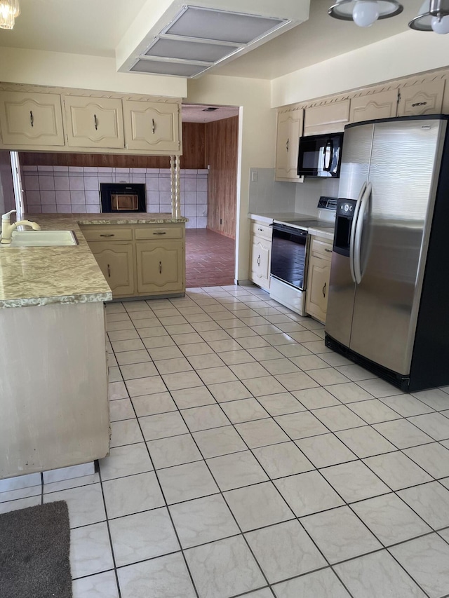 kitchen with electric range, black microwave, a sink, light countertops, and stainless steel refrigerator with ice dispenser