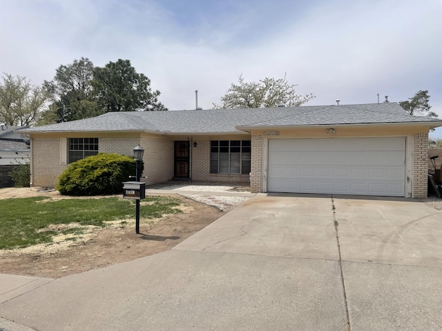 ranch-style house with brick siding, a garage, roof with shingles, and driveway