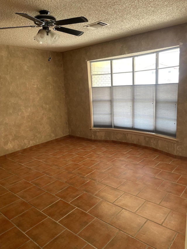 empty room featuring visible vents, a ceiling fan, and a textured ceiling